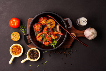 Grilled prawns served on a plate with lemon. Garlic on dark black background. Seafood. Top view.