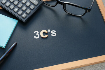 Business, marketing, and education concept. The letters 3C's on the black chalkboard with eyeglasses, calculator, pen, and Post-it Note at the side