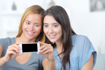 two young ladies taking selfie with cellphone