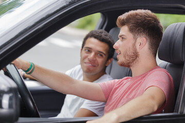 two male friends relaxing in car during road trip