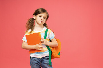 A little girl with a backpack on her shoulder and textbooks