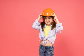 Little girl in construction helmet on pink background, place for text