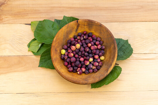 Grewia asiatica falsa fruit in wooden bowl top view on a wooden table background