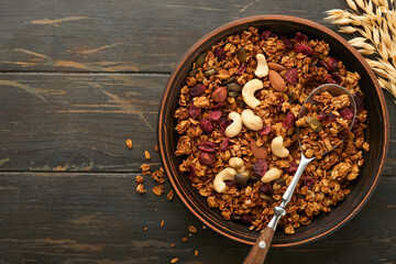 Obraz na płótnie Canvas Homemade granola with greek yogurt or milk and cashews, almonds, pumpkin with dried cranberry seeds in old bowl on old rustic wooden background. Healthy energy breakfast or snack. Top view.