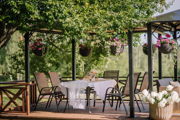 A white table is laid on the terrace and decorated with flowers in summer, which are hung in pots at sunset