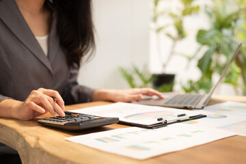 Asian businesswomen calculate financial graphs showing results about their investments and planning successful business growth process in the office