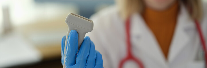 Ultrasonic machine sensor in hands of doctor therapist in clinic closeup. Ultrasound examination of...