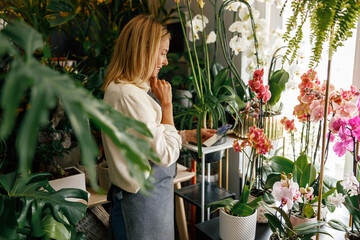 Woman florist writing orders and customer information in notebook at flower shop. High quality photo