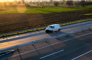 White delivery van on the highway. White modern delivery small shipment cargo courier van moving fast on motorway road to city urban suburb. The world's best transport of goods.
