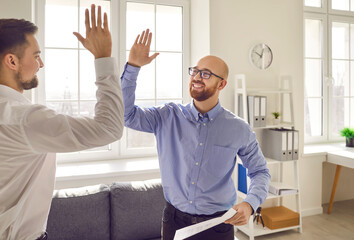 Businessman giving high five to his partner at meeting in office. Business team celebrating...