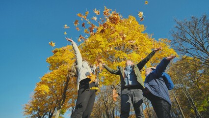 A young, happy family in the park sprinkled with leaves.