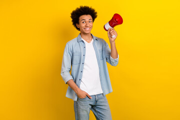 Photo of cheerful positive guy dressed denim shirt rising loud speaker isolated yellow color background