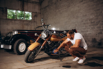 A man wipes the engine of a retro motorcycle. Retro collector of cars and motorcycles