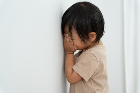little asian children kid girl covering his eyes with hands, playing hide and seek standing next a wall house, Adorable child having fun in the home. happy family have fun with kids, activity