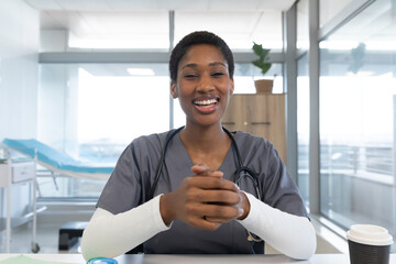 African american female doctor wearing scrubs and stethoscope, having video call at hospital - obrazy, fototapety, plakaty