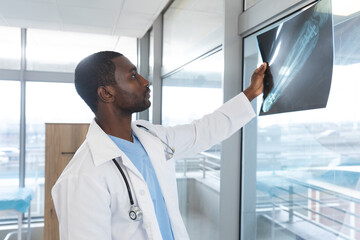 Fototapeta premium African american male doctor wearing lab coat and stethoscope, holding x-ray scan