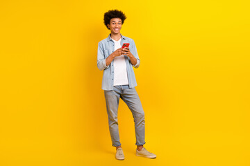 Full size portrait of handsome man hold use smart phone chatting isolated on yellow color background