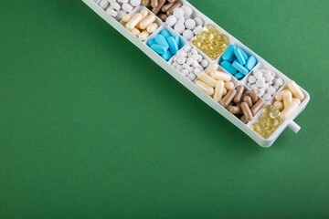 Box with different pills on a green background