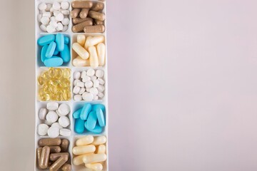 Box with different pills on a pink background