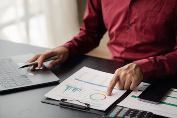 Business man checking financial documents, he owns a startup company, he sits checking the company's financial summary prepared by the finance department. Management concept of startup company..
