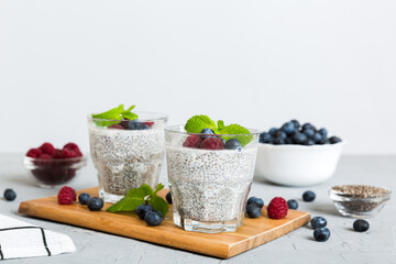 Healthy breakfast or morning with chia seeds vanilla pudding raspberry and blueberry berries on table background, vegetarian food, diet and health concept. Chia pudding with raspberry and blueberry