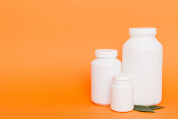 supplement pills with medicine bottle health care and medical top view. Vitamin tablets. Top view mockup bottle for pills and vitamins with green leaves, natural organic bio supplement, copy space