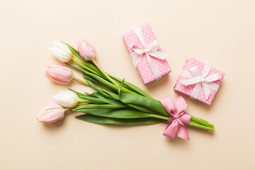 Pink tulips flowers and gift or present box on colored table background. Mothers Day, Birthday, Womens Day, celebration concept. Space for text top view