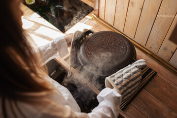 Girl hostess taking hot pot from the oven with baked bread. Hot pot with steam around, baking at home concept