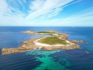 Aerial shot of an island surrounded by the crystal clear sea on a sunny day