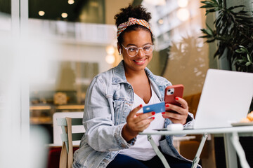 Woman smiling and using mobile for online payment - obrazy, fototapety, plakaty