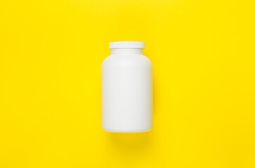 Plastic bottle with vitamins on color background, top view