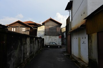 Fototapeta na wymiar Narrow street with old residential buildings and a parked car. Penang, Malaysia.