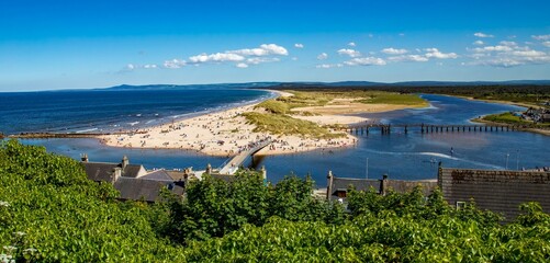 Scenic beach from a vantage point atop a hill, featuring the pristine blue waters and two bridges