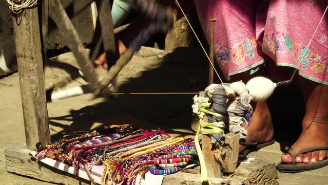 Old lady weaving traditional cloth called sarong in Sade village - feet level shot