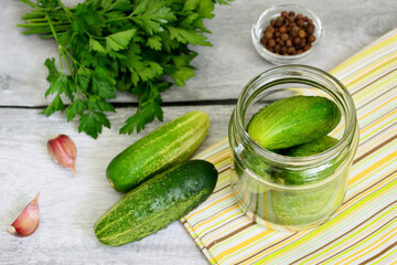 green cucumbers in jar with garlic, allspice and parsley  