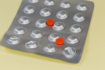 Red pills lie on foil blister pack close-up