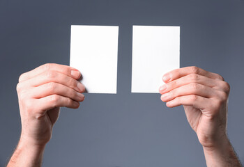 Man holding paper cards on grey background, closeup. Mockup for design
