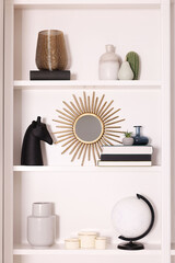 Interior design. Shelves with stylish accessories and books near white wall
