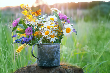 Summer background. flowers in old metal cup close up on meadow, abstract natural background. Useful...