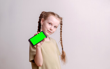 Cute school-age girl holding a smartphone against a white background