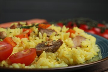 Delicious pilaf with meat and tomatoes on plate, closeup