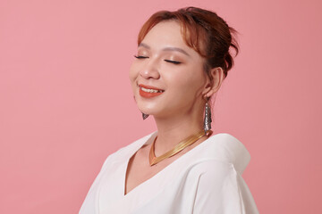 Happy transgender woman closing eyes and smiling, isolated on pink