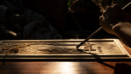 An old Chinese carpenter is carving words on a wooden board, traditional technique, indoor shooting, partial close-up(Translation: The carved text reads 