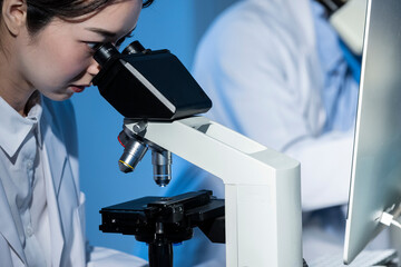 A female scientist conducting research under a microscope
