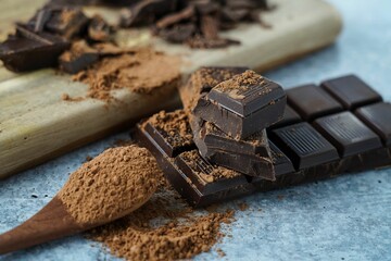 a wooden spoon filled with chocolate powder near chocolate bar