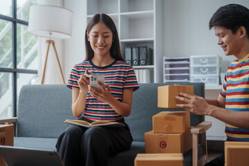 Two chinese couple startup small business owner packing goods for delivery to clients. Freelancer SME man and woman selling online product on social media application and short reel video.