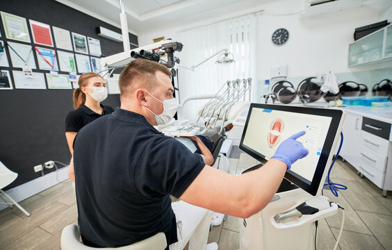 Dentist scanning patient's teeth with modern machine for intraoral scanning. Digital print of patient's teeth is on big screen. Modern high precision technologies. Concept of modern dentistry