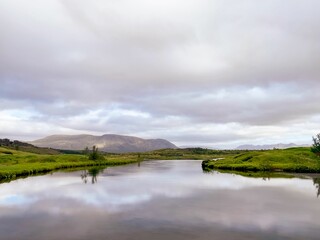 Obraz premium Idyllic landscape featuring a tranquil river winding its way through a lush green field in Iceland