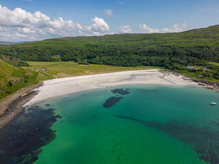 An aerial drone photo of Calgary Bay. This beautiful beach can be found on the Isle of Mull in Scotland. The beach has white sand and turquoise water. 