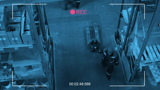 High angle view CCTV shot of ethnically diverse men and woman walking along warehouse discussing plans and pulling pallet jack